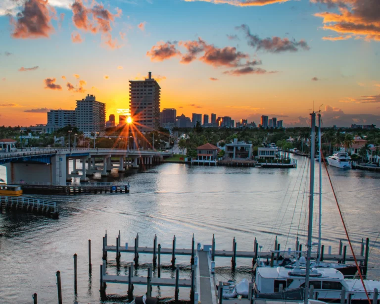 Sunset over a marina and drawbridge with a city skyline in the distance