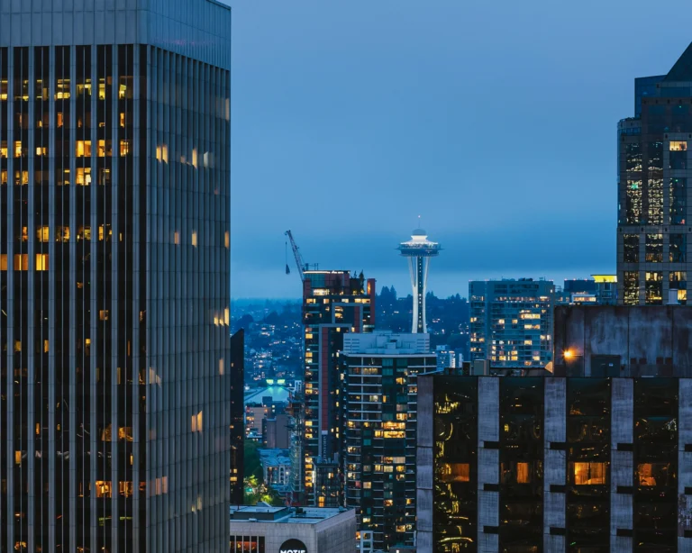 Space Needle framed between downtown Seattle high-rises at dusk